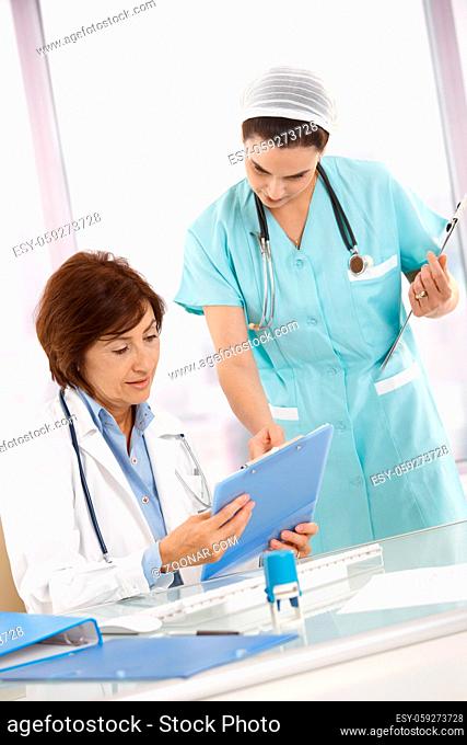 Nurse and doctor working in office, analysing diagnosis together