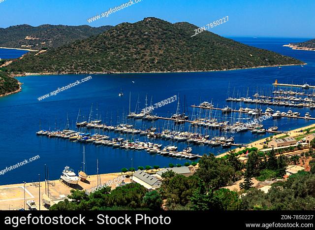 KAS, ANTALYA - JULY 19, 2015 : Seascape of Kas Marina with yahts and boats, touristic small town of Antalya, surrounded with high mountains with trees