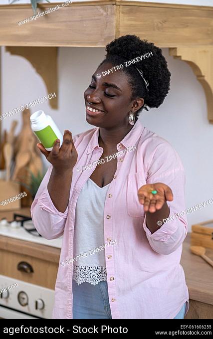 Heathcare. Young african woman taking vitamins and smiling