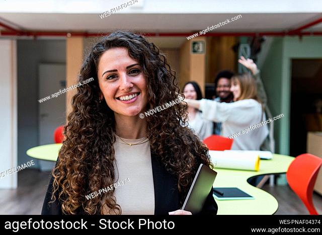 Portrait of a smiling brunette businesswoman holding laptop in office