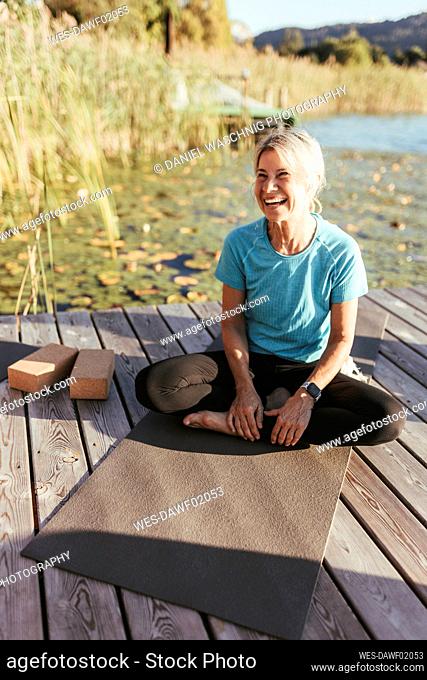 Happy woman looking away while sitting on exercise mat at yoga class