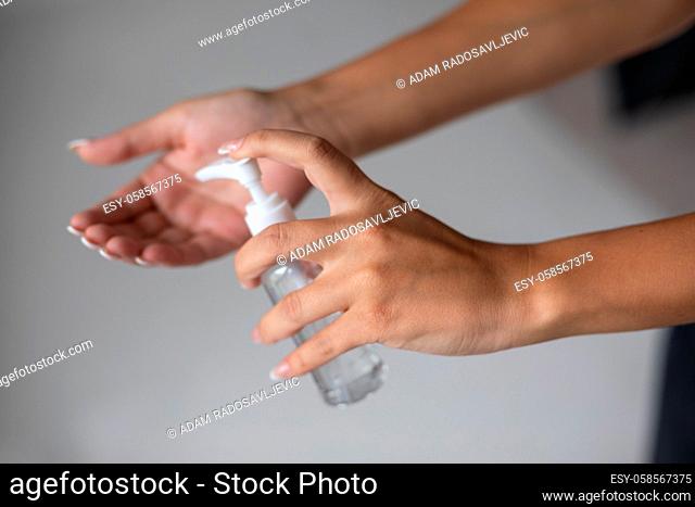 Close up view of woman person using small portable antibacterial hand sanitizer on hands. Stock photo
