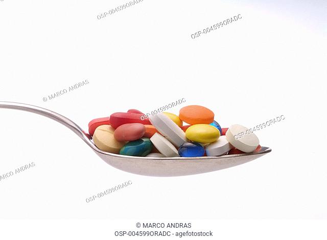a spoon full of colored drugs and pills