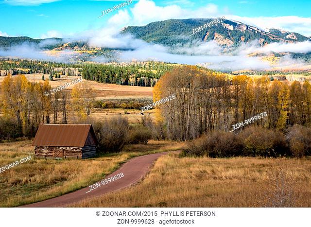 Country Barn is near a rural road in Colorado. The one-lane road winds through to the group of trees on the right. In the background of the picture is a small...
