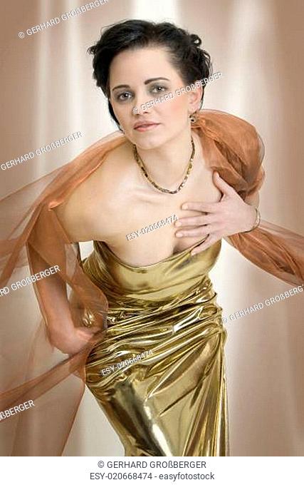 Junge elegante Dame in Kleid aus Gold und Schal