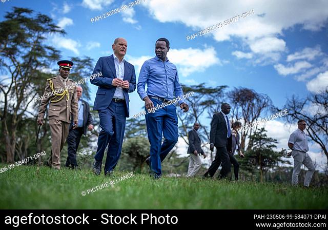 06 May 2023, Kenya, Olkaria: German Chancellor Olaf Scholz (SPD) listens to hydrologist Luke Olang (M) explain the ecological and economic changes at Sopa Lodge...