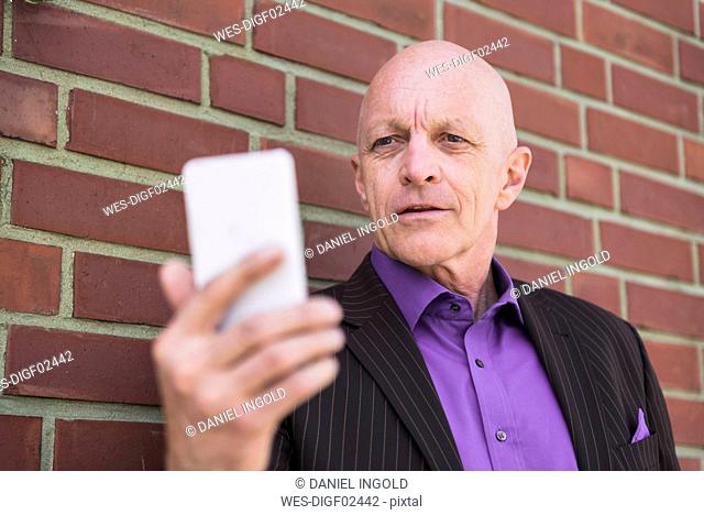 Businessman at brick wall using cell phone
