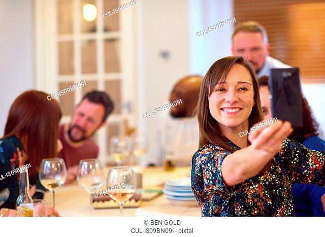 Friends taking selfie at dinner party