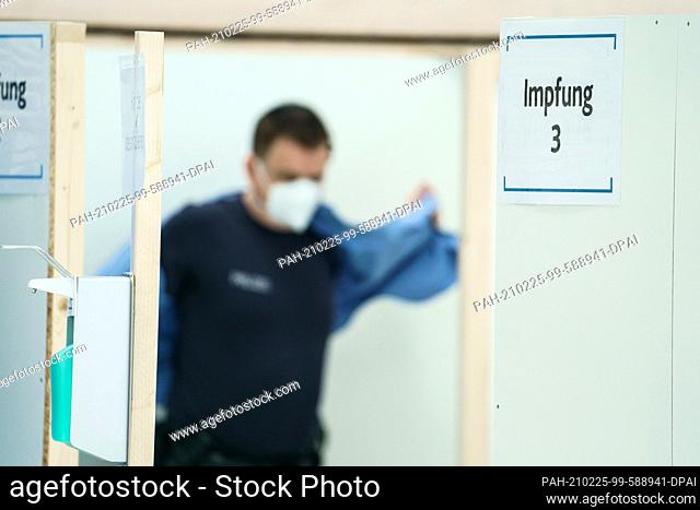 25 February 2021, Rhineland-Palatinate, Mainz: A police officer prepares to be vaccinated with Astrazeneca vaccine at a police vaccination center at the...
