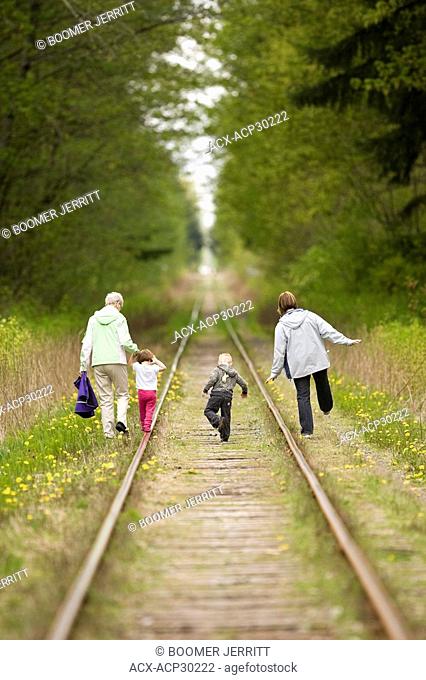 A family of three generations, walks along railroad tracks near the Miillard Greenway in Courtenay. Courtenay, The Comox Valley, Vancouver Island