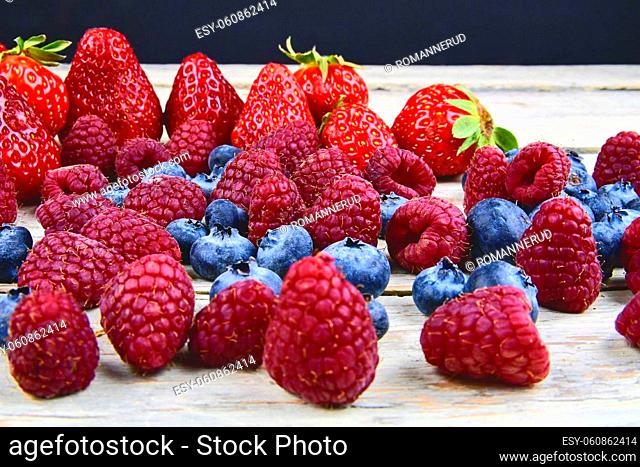 Healthy mixed fruit and ingredients with strawberry, raspberry, blueberry. Berries on rustic white wooden background. Free space for text