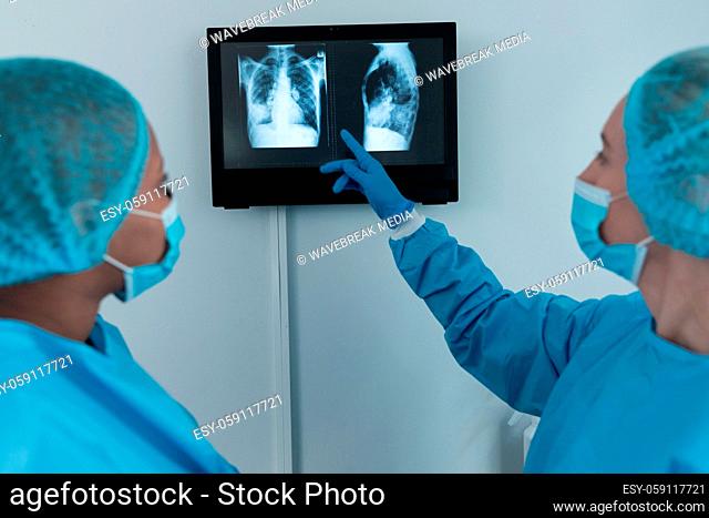 Diverse couple of female surgeons in operating theatre wearing face masks looking at screen