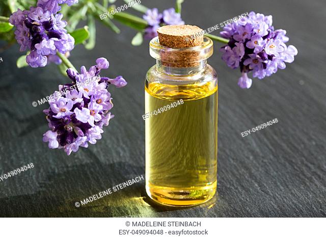 A bottle of lavender essential oil with fresh lavender twigs in the background