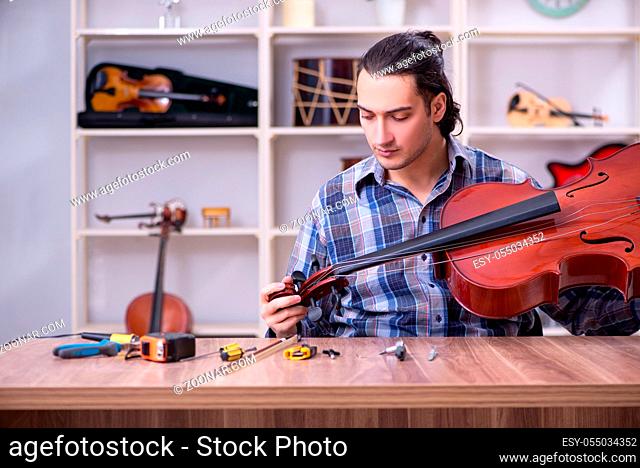 Young handsome repairman repairing violin