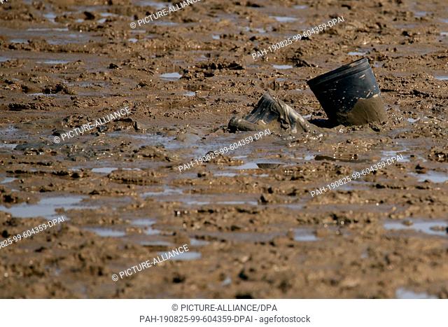 25 August 2019, Lower Saxony, Cuxhaven: Rubber boots are stuck in the mud flats. Photographers who were not paying attention were stuck in the mudflats of the...