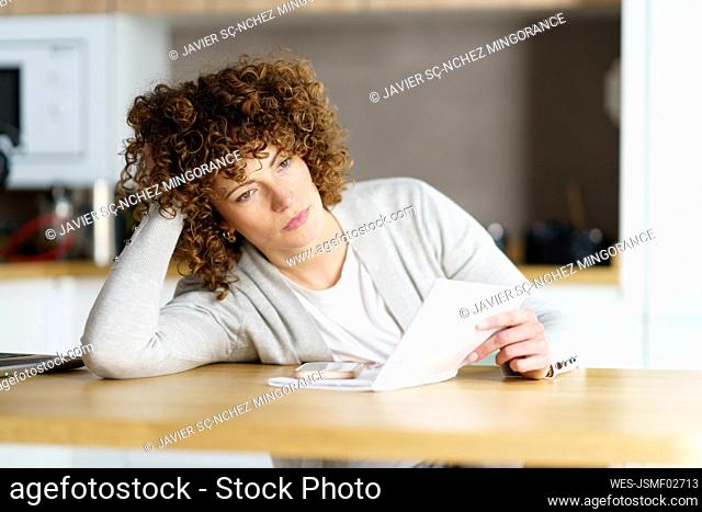 Thoughtful freelancer with note pad and smart phone leaning on desk