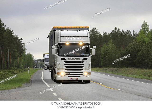 Raasepori, Finland. May 24, 2019: White Scania R440 semi trailer with high beams on briefly and another truck haul goods on road in South of Finland