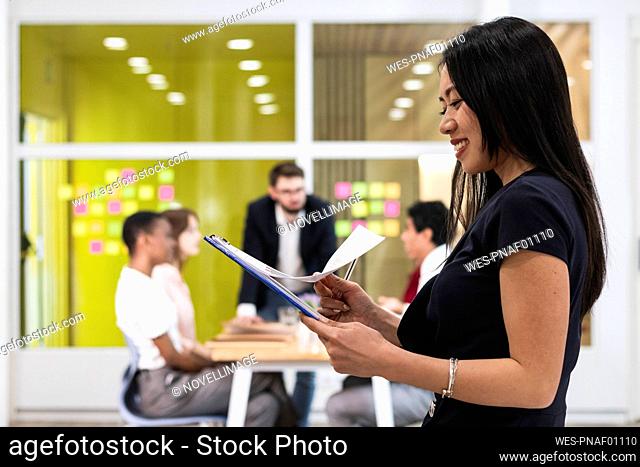 Smiling businesswoman checking documents in office
