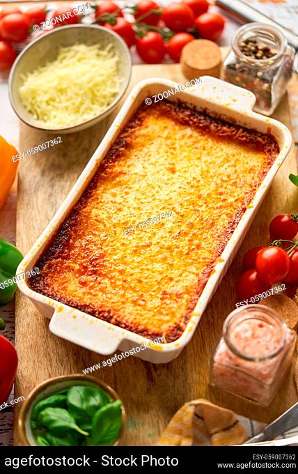 Tasty traditional italian lasagna with bolognese, melted and cheese. Served with ingredients. Placed on a wooden background. Top view, flat lay