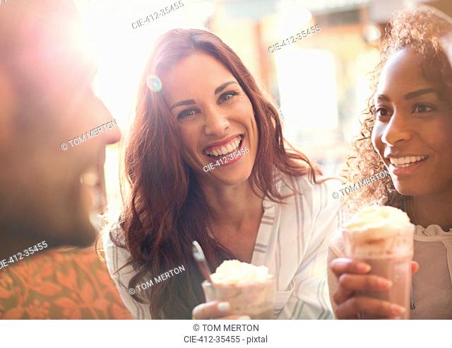 Portrait enthusiastic young woman drinking milkshake with friends
