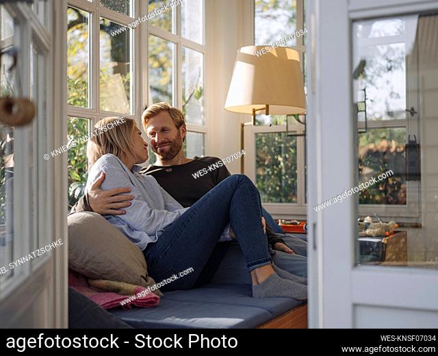 Affectionate couple relaxing in sunroom at home