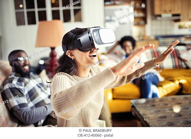 Woman gesturing, using virtual reality simulator glasses in living room