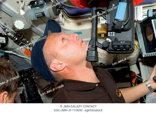 Astronaut Doug Hurley, STS-127 pilot, uses a High Definition Video (HDV) camera at an overhead window on the aft flight deck of Space Shuttle Endeavour during...