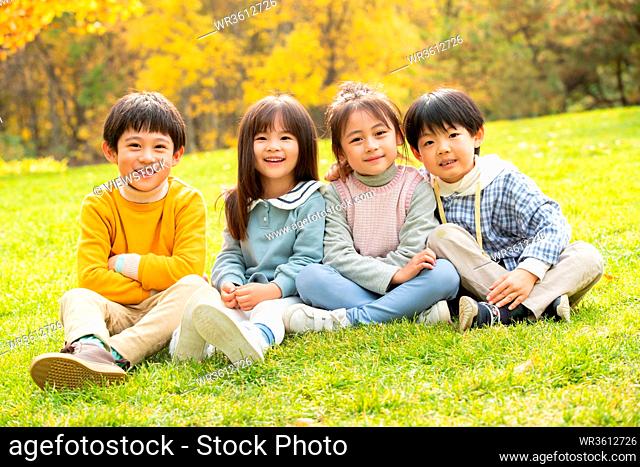 Lovely children sitting on the grass to play