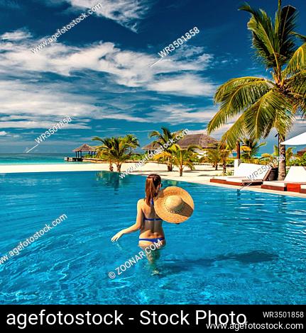 Woman with sun hat at beach pool in Maldives