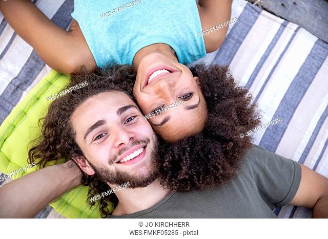 Portrait of happy couple lying on a blanket outdoors