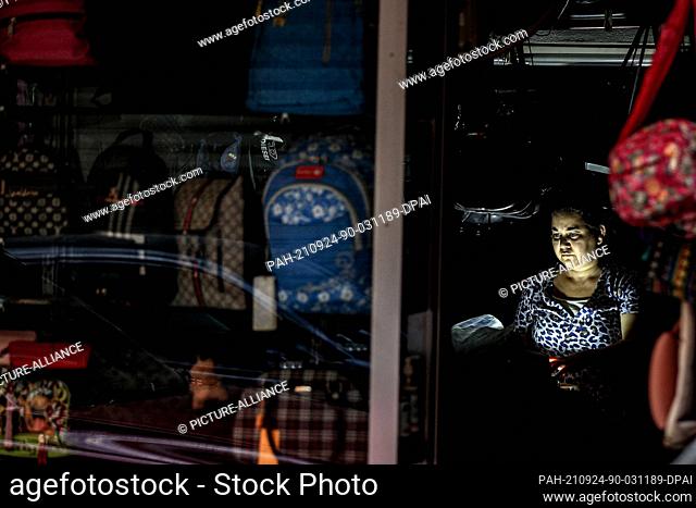 24 September 2021, Lebanon, Beirut: A Lebanese woman sits inside a suitcases shop during an electricity outage. Photo: Marwan Naamani/dpa