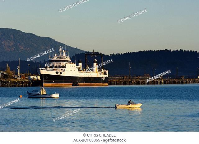 Small power boat leaves harbour, Cowichan Bay, Vancouver Island, British Columbia, Canada
