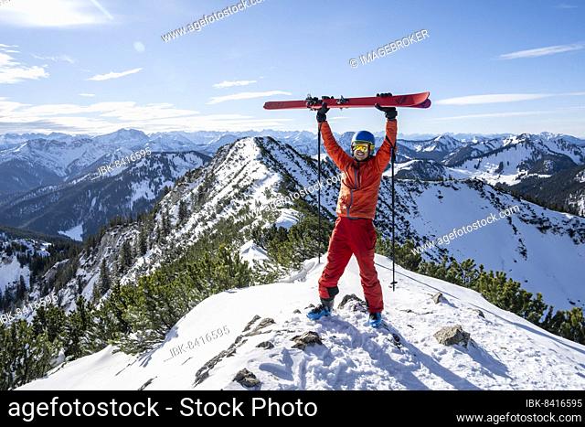Ski tourer lifts his skis into the air at the summit of Jagerkamp, winter, Bavaria, Germany, Europe