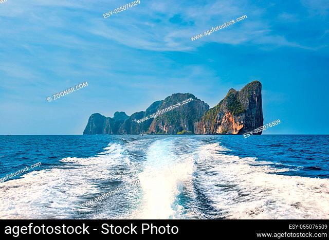 Panorama of famous Phi Phi island in Thailand with white waves stream behind speed boat, sea and mountains in beautiful lagoon