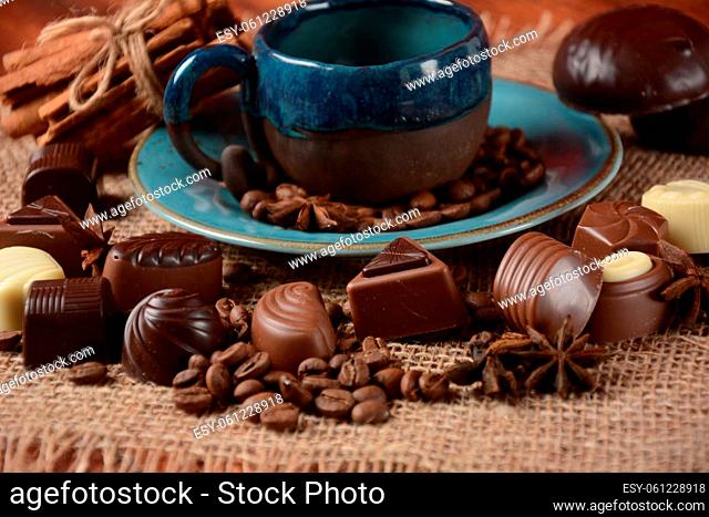 Coffee cup, beans, chocolate on old kitchen table Assortment of dark, white and milk chocolate sweets, zefir (zephyr). Spices, cinnamon