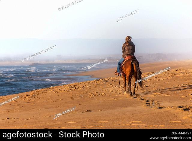 Woman Riding Horse Into the Fog on the Beach at Sunset on Salinas State Beach, California