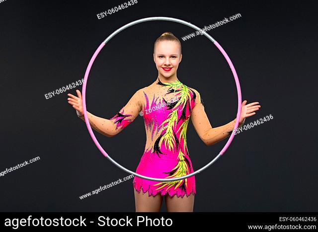 beautiful blond teen age gymnast girl making exercises with hula hoop. Studio shot on black background. Copy space