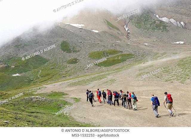 A group of hikers in single line formation cross the plateau called Piano dei Camosci, Lepontine Alps  Formazza  Italy