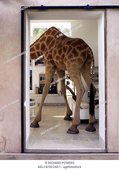 Headless body of model giraffe standing in doorway of living area in Moroccan home