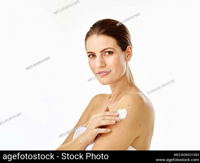 Portrait of smiling woman applying body cream on her arm
