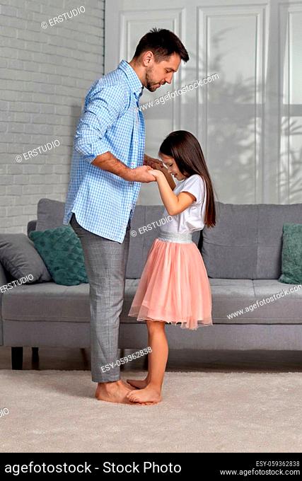 Handsome young father dancing with his little cute daughter at home