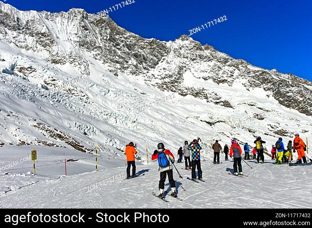 Skifahrer auf dem Weg zur Längfluh Abfahrt, hinten Feegletscher und die Gipfel Dom und Lenzspitze der Mischabelhörner, Skigebiet Saas-Fee, Wallis