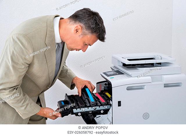 Mature businessman fixing cartridge in photocopy machine at office