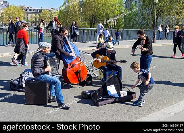 PARIS, FRANCE - APRIL 2, 2017: Street musicians in retro style on a Saint-Louis bridge, Paris, France. A sunny day in early April
