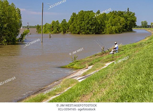 Carville, Louisiana - A man fishes on the bank of the rain-swollen Mississippi River