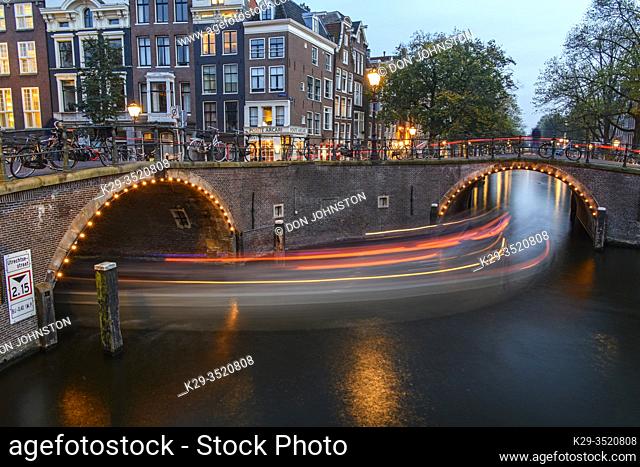 Reflections of bridge lighting in canals at dusk, Amsterdam, North Holland, Netherlands