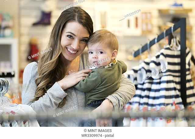 Caucasian mother and baby son shopping in clothing store