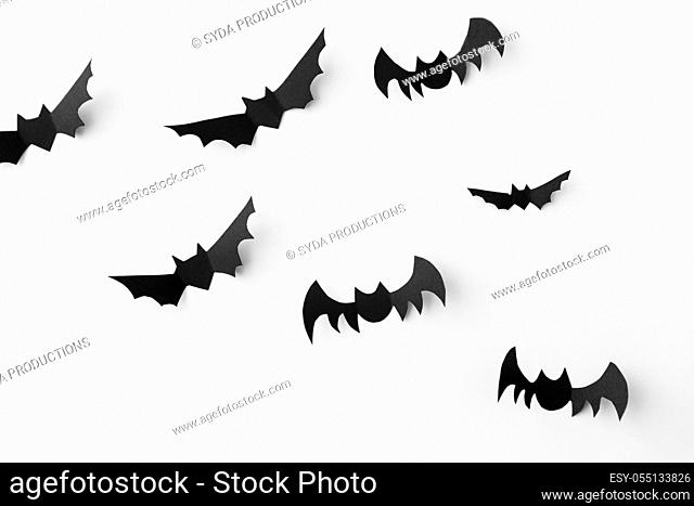 flock of black paper bats over white background