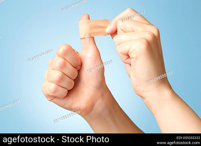 Woman putting a plaster on her thumb