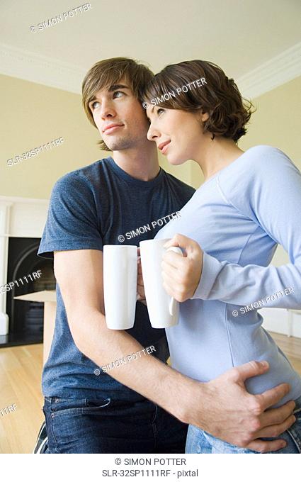 Couple hugging with coffee in new home
